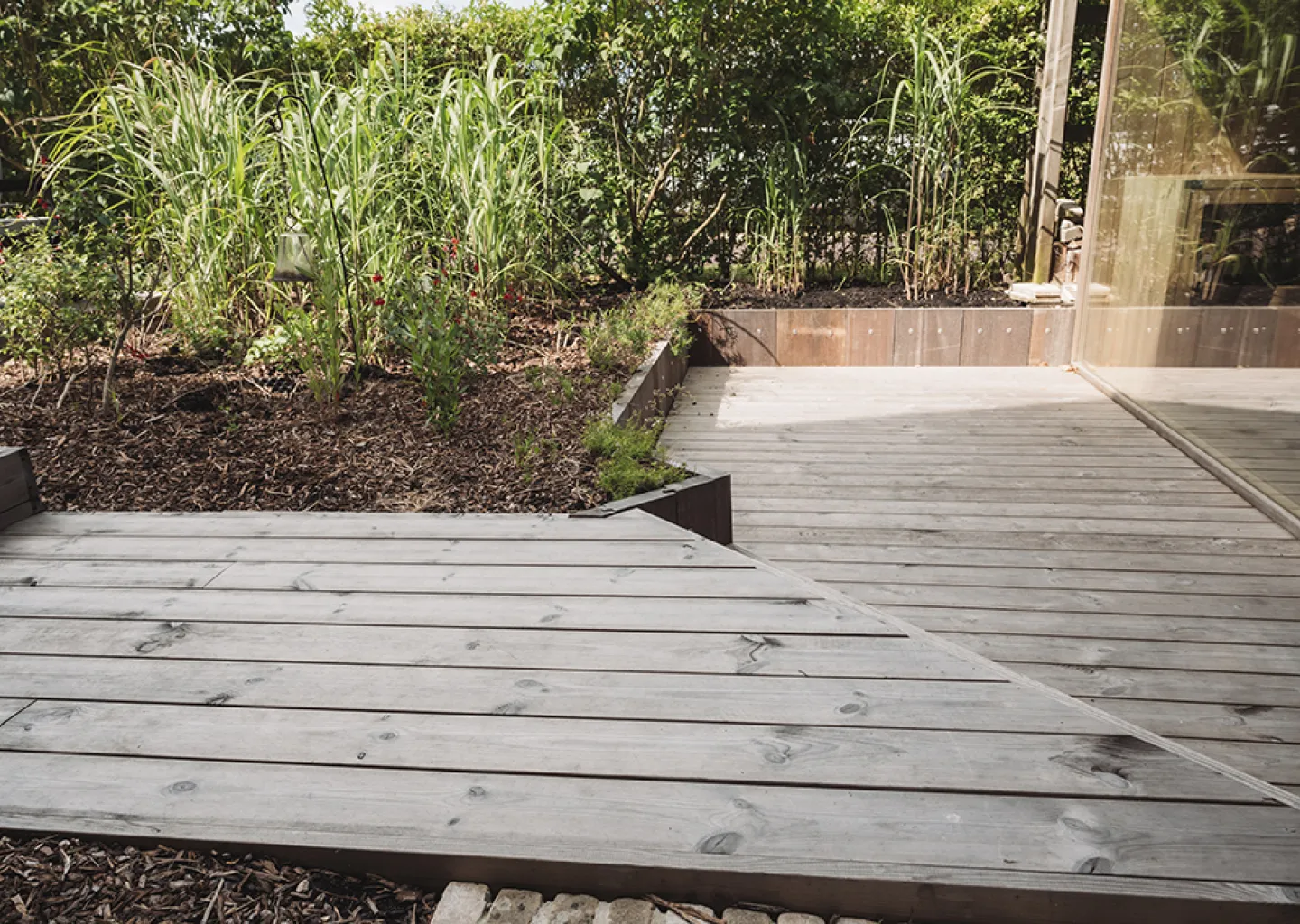 Houten terassen in een tuin aangelegd door Tuinen Cobbaert