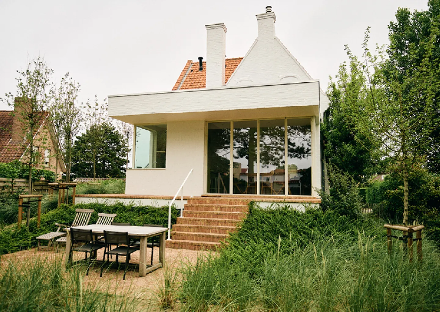 Tuinen Cobbaert ontwerpt een kusttuin met terras siergrassen en een natuurlijke overgang naar de woning